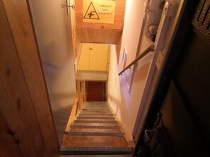 A narrow stairway leading to a room with a wooden door and a caution sign.