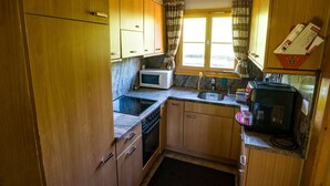 A compact kitchen with wooden cabinets, a microwave, a sink, and a stove.