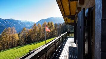 Ein Holzbalkon mit Blick auf ein Gebirge und eine Flagge.