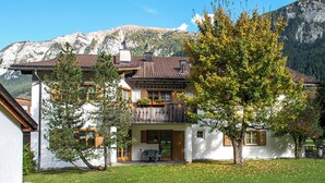 Un bâtiment à deux étages doté d’un balcon, d’une pelouse et ayant des montagnes en toile de fond.