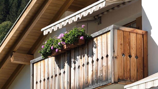 Un balcon en bois orné de jardinières et un mur blanc.