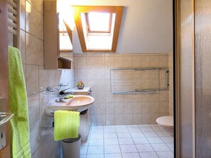 Ein Badezimmer mit Oberlicht, Waschbecken, Toilette und Handtuchhalter.