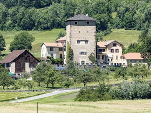 Una torre de piedra con techo plano, rodeada de edificios residenciales con tejados a dos aguas.