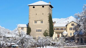 A historic tower building with a snow-covered roof, surrounded by traditional buildings with multiple windows and a clear blue sky.