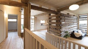 Ein Holzinnenraum mit Balkon, einer Hängelampe und Blick ins Freie.