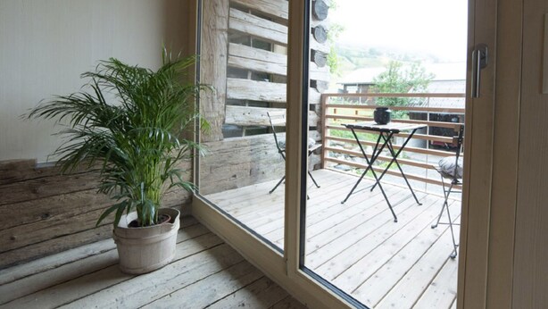 Eine Holzterrasse mit einem Blumentopf, einem Tisch und Stühlen.