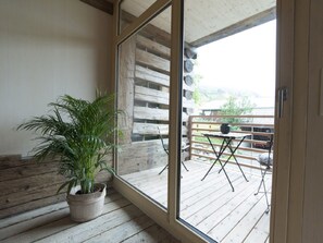 Una terraza de madera con una maceta, una mesa y sillas.
