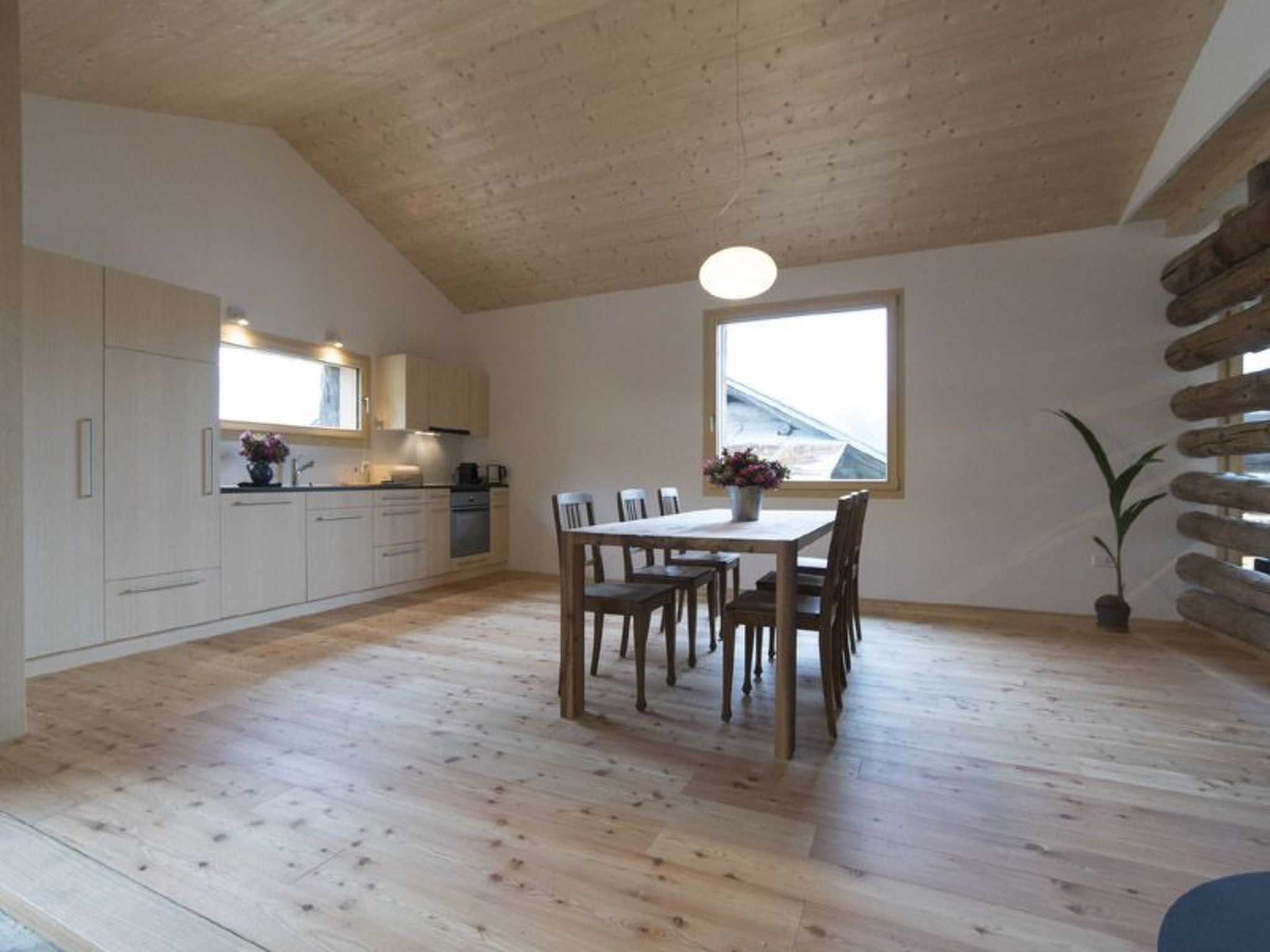 Una cocina amplia con armarios de madera, una mesa de comedor con sillas y un ventanal grande.
