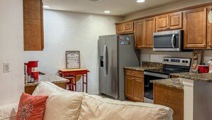 A modern kitchen with wooden cabinets, a stainless steel refrigerator, a microwave, and an oven. - Amazing Retreat in Lehigh Acres Florida (Lehigh Acres)