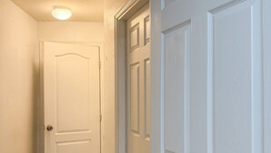 A hallway with a white door, a wooden floor, and a ceiling light. - Amazing Retreat in Lehigh Acres Florida (Lehigh Acres)