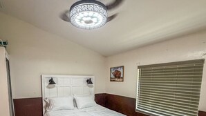 A bedroom with a bed, a nightstand, a ceiling fan, a window with blinds, and a wall-mounted picture. - Amazing Retreat in Lehigh Acres Florida (Lehigh Acres)
