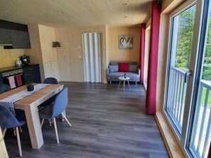 A modern interior with a dining area, a sofa, and large windows. - Ferienwohnungen Aktien 11, (Sils i.D.), by Interhome (Sils im Domleschg)