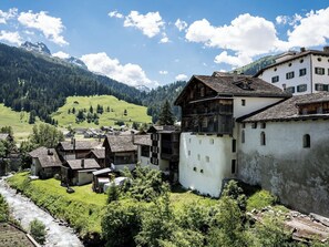 Ein traditionelles Dorf mit rustikalen Häusern, einem Fluss und Bergen im Hintergrund.