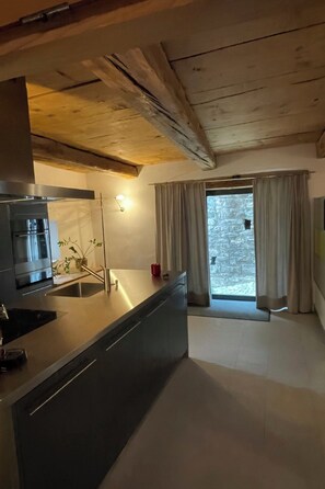 Eine moderne Küche mit Backofen, Spüle und einem Fenster mit Vorhängen.