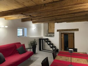 Ein gemütliches Wohnzimmer mit einem roten Sofa, einem kleinen Tisch und einer Treppe, die zu einer oberen Ebene führt.
