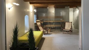 Un intérieur moderne avec une cloison en verre, des poutres en bois au plafond et des espaces aménagés pour s’asseoir.