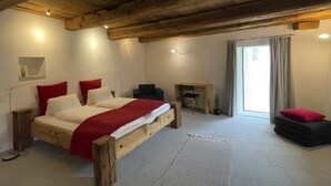 Une chambre à coucher avec un lit en bois, un bureau, une chaise, une petite table et une fenêtre avec des rideaux.