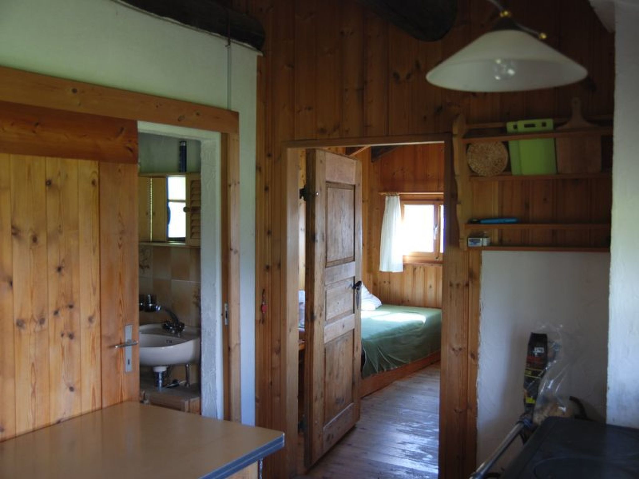 Un interior de madera con una zona de cocina, un baño y una zona de descanso con una cama.