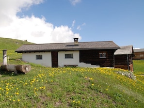 A traditional wooden house with a sloped roof, a chimney, and a small porch area.