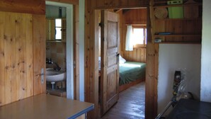 Un interior de madera con una cama, un lavabo y un ventilador de techo.