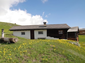 Una casa de fusta tradicional amb teulada inclinada, una xemeneia i una finestra petita.