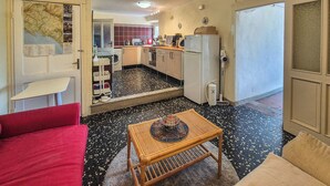 Un espacio habitable compacto con kitchenette, una zona de comedor con mesa y sillas, y un sofá rojo.