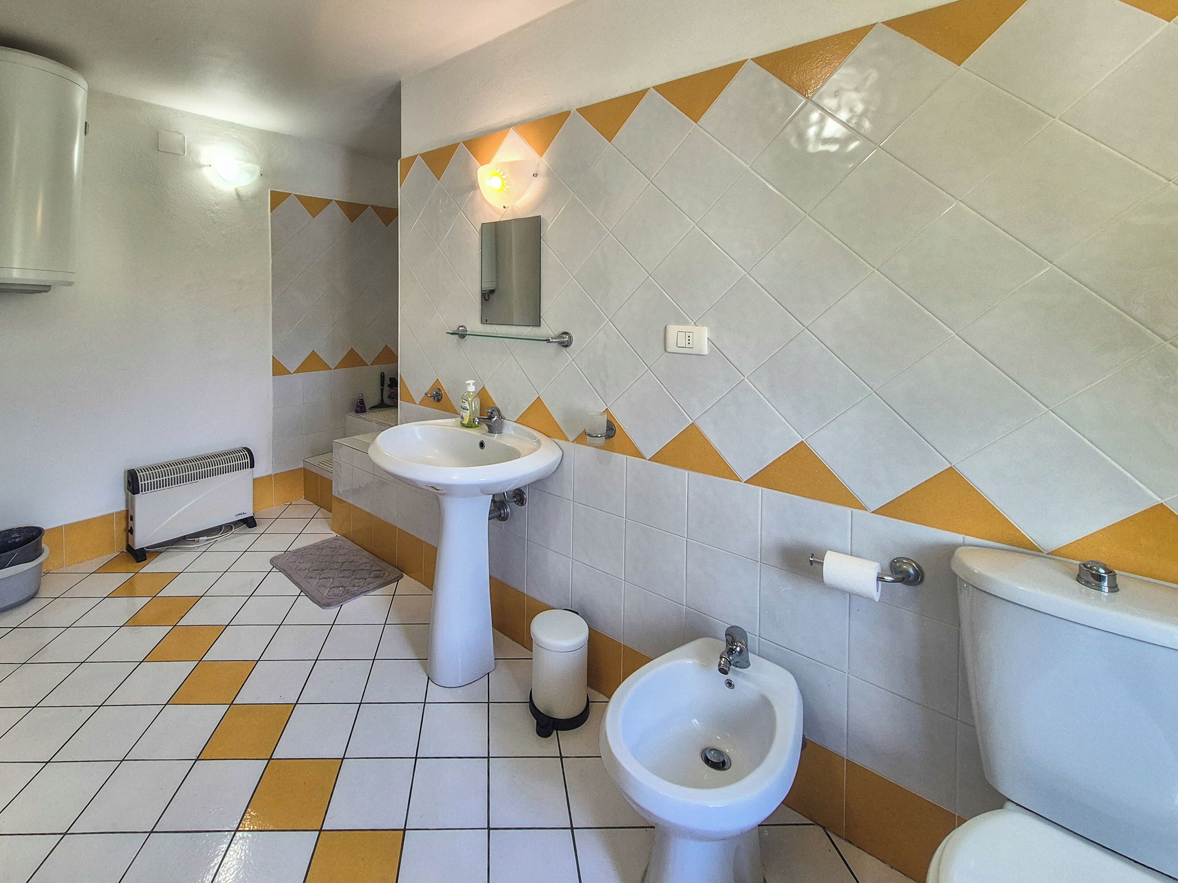 Een badkamer met twee wasbakken, een bidet, een toilet en een radiator.