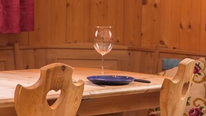 A wooden dining table with a glass of water, a blue plate, and a knife.