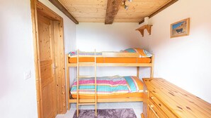 A room with a bunk bed, wooden wardrobe, and a ceiling fan.