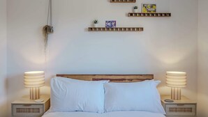 A neatly made bed with two bedside lamps, a wooden headboard, and wall-mounted shelves with decorative items. - Host & Stay | Austin House (Norwich)