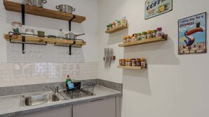 A kitchen with wooden shelves holding pots, jars, and a coffee sign. - Host & Stay | Austin House (Norwich)
