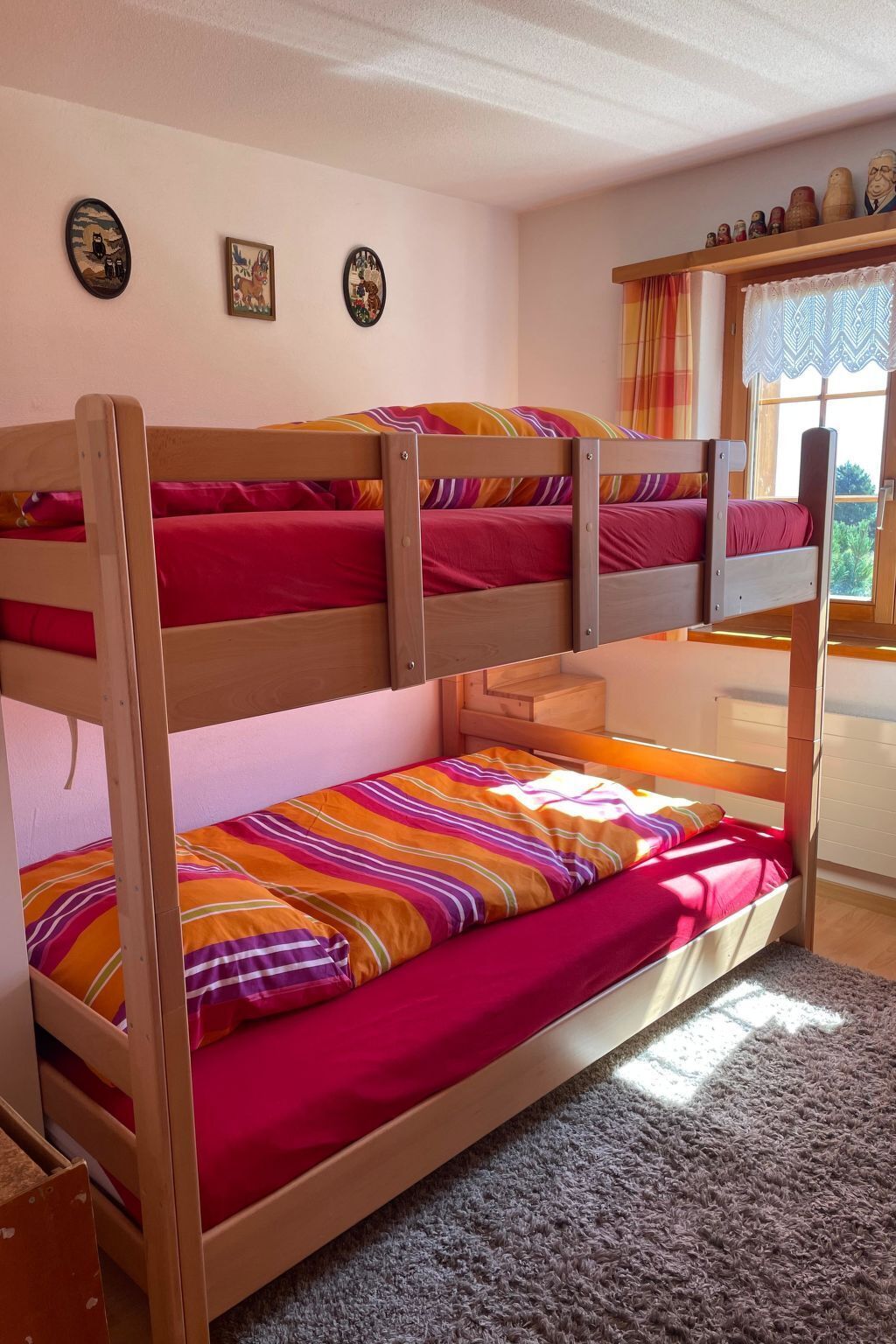 Una camera con letto a castello, una finestra, un tavolino e decorazioni alle pareti.