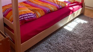 A bunk bed room with a window, a small table, and wall decorations. - Baria Sut 5, (Oberurmein), by Interhome (Urmein)