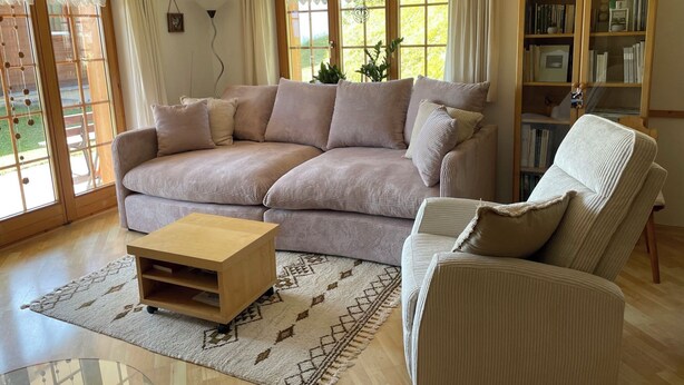 A living room with a sofa, a chair, a coffee table, and a bookshelf. - Baria Sut 5, (Oberurmein), by Interhome (Urmein)