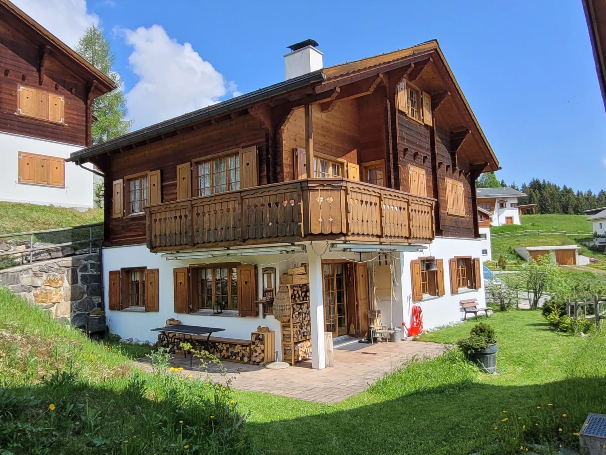 Una casa a due piani in legno, con balcone, fondamenta in pietra e un giardino.