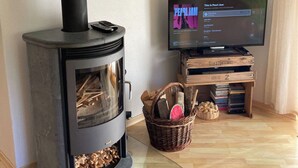 A modern living room with a wood-burning stove, a television, and a bookshelf. - Baria Sut 5, (Oberurmein), by Interhome (Urmein)