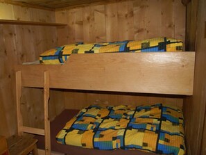 Een stapelbed met een houten frame en een gewatteerde spreidekker.