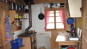 Une cuisine rustique avec des meubles en bois, un poêle et une fenêtre ornée de rideaux à carreaux.