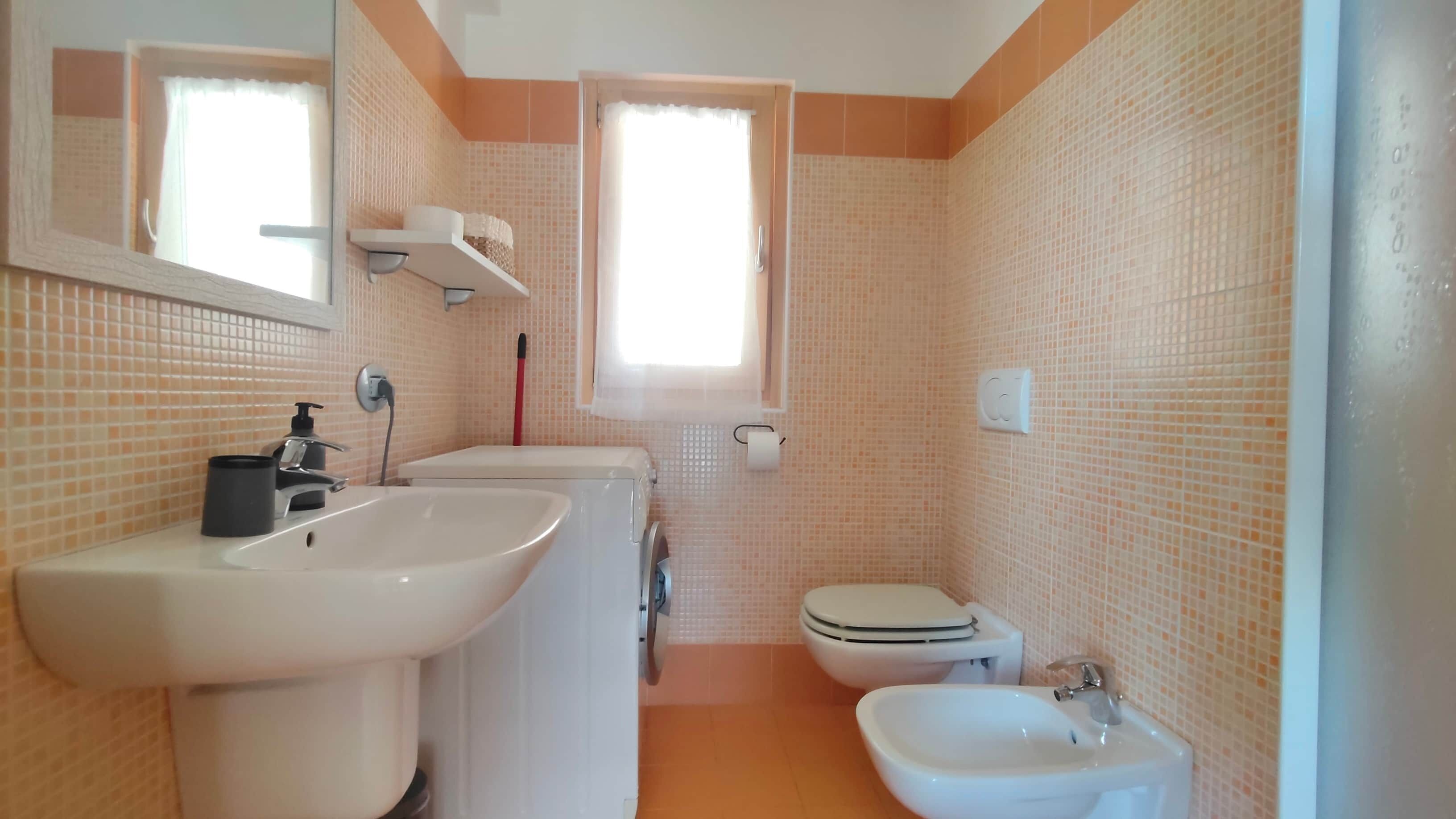 A bathroom with a sink, toilet, bidet, and mirror.
