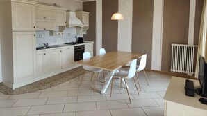 A modern kitchen with white cabinets, a dining table with chairs, and a pendant light. - Apartments Chalet al Lac - Flowers - Pool & Lake Como View (San Gregorio)