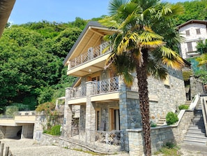 Ein Steinhaus mit Balkon, Treppe und einer Palme.
