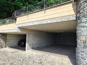 A stone building with a covered parking area and a metal railing on the upper level. - Apartments Chalet al Lac - Flowers - Pool & Lake Como View (San Gregorio)