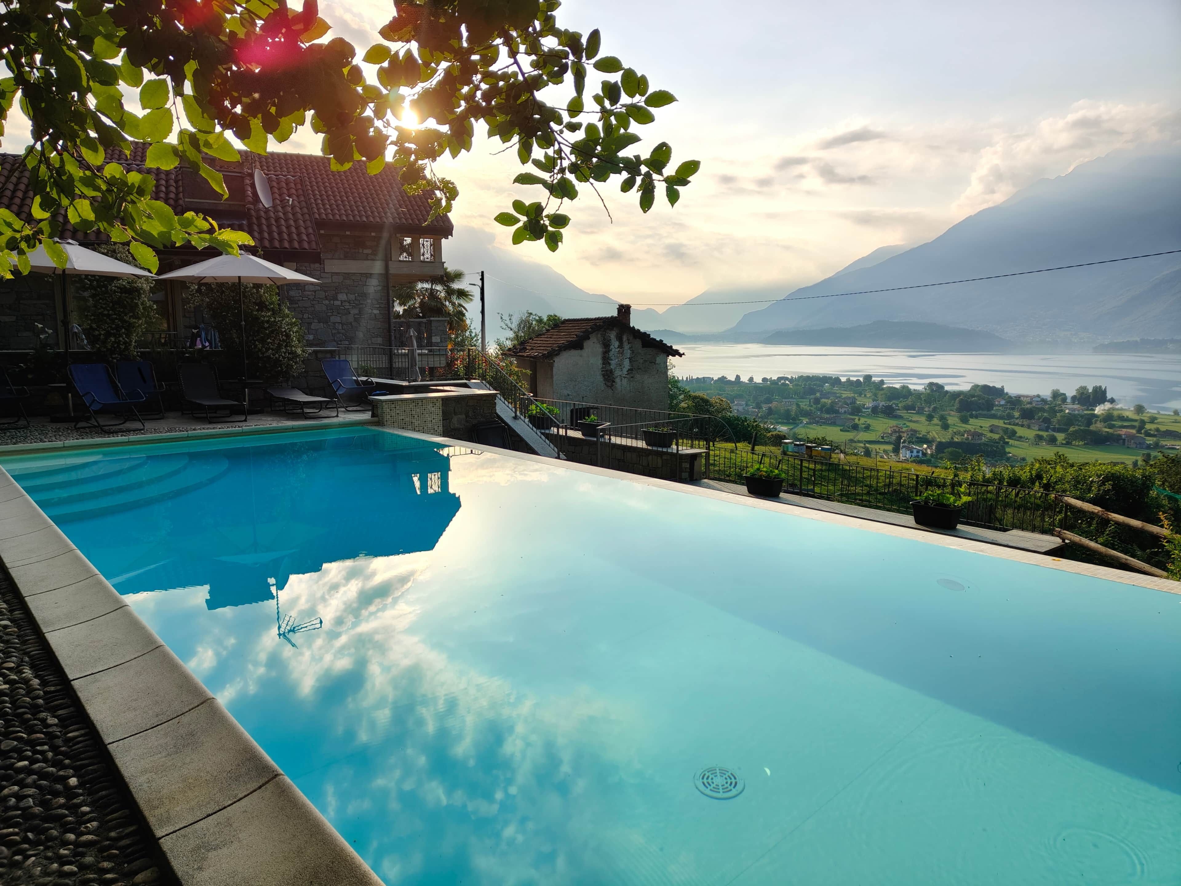 A swimming pool with a clear view of a mountainous landscape and a body of water.