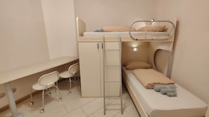 Ein Etagenbett mit Schreibtisch, Stühlen, einer Leiter und einem kleinen Nachttisch.