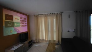 Ein Wohnzimmer mit Flachbildfernseher, Couch und Couchtisch aus Holz.