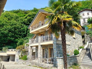 Un edificio de piedra con balcón, escaleras y una palmera.