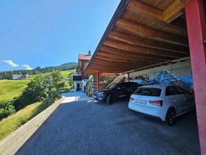A parking area with a white car and a black SUV, a building with a sloped roof, and a view of a green landscape with houses. - im Försterhaus Dalin, (Dalin), by Interhome (Dalin)