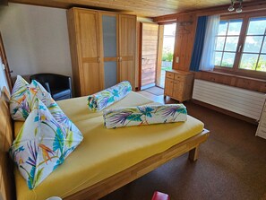 A room with a bed, a chair, a wooden wardrobe, and a window with a view. - im Försterhaus Dalin, (Dalin), by Interhome (Dalin)
