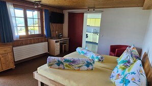 Una habitación de madera con una cama, un escritorio y vistas a una cocina.