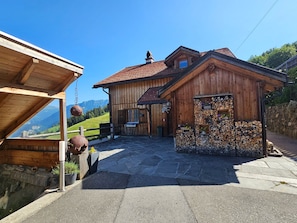 A wooden building with a stone-paved entrance, a wooden fence, and a view of mountains in the background. - im Försterhaus Dalin, (Dalin), by Interhome (Dalin)